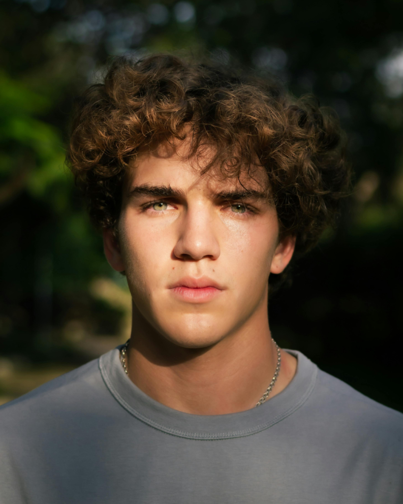 Male Model With Dense, Healthy Brown Curly Hair And Green Eyes, Representing Effective Male Hair Restoration New York Services For Natural Results | Hair Regrow Solutions | Hair Loss Consultations